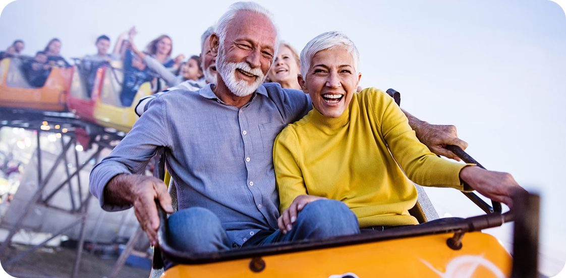Elderly couple enjoying a roller coaster ride.