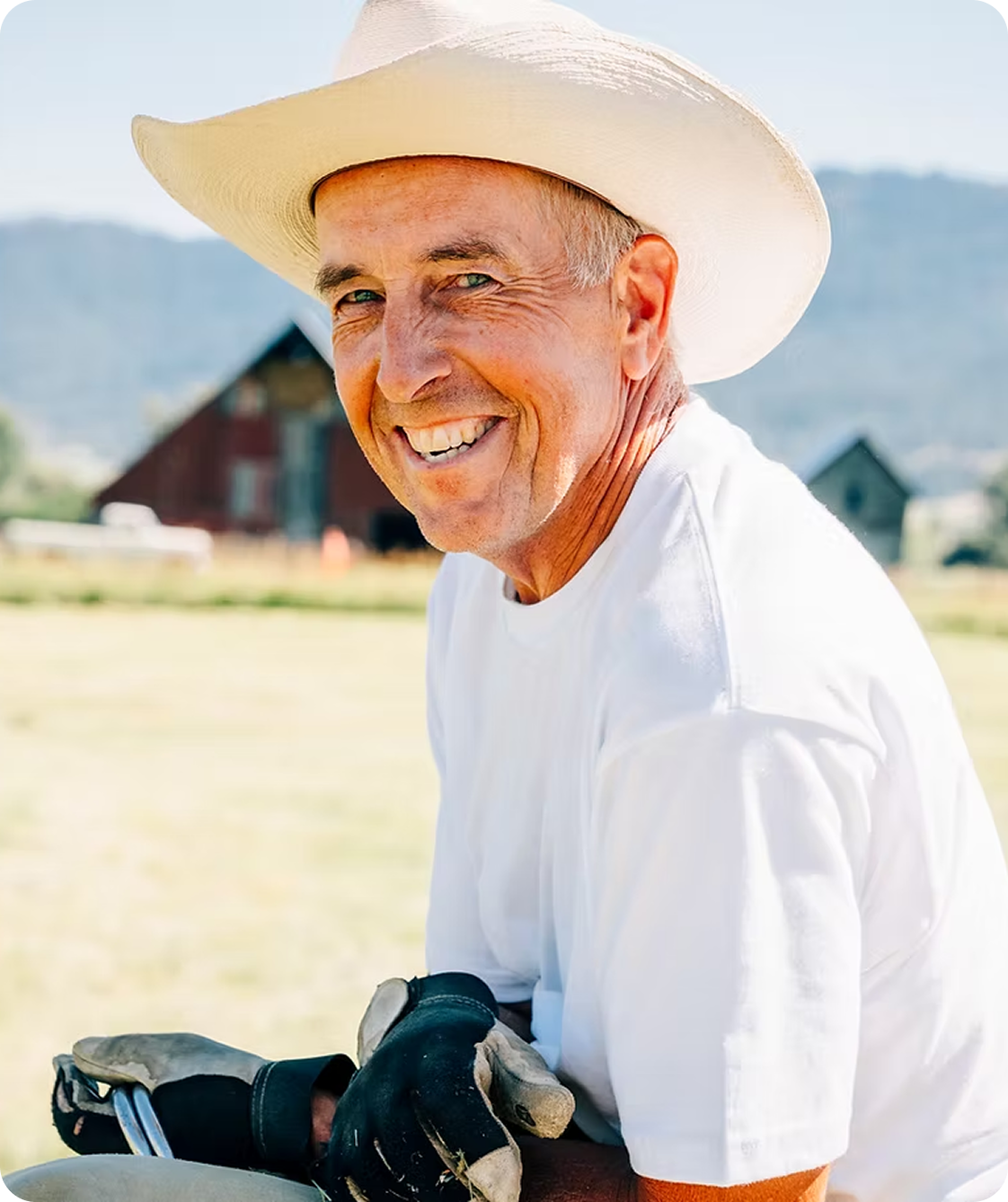 Smiling man wearing cowboy hat outdoors.